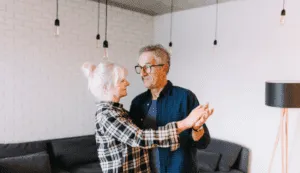 two older adults dancing in a living room