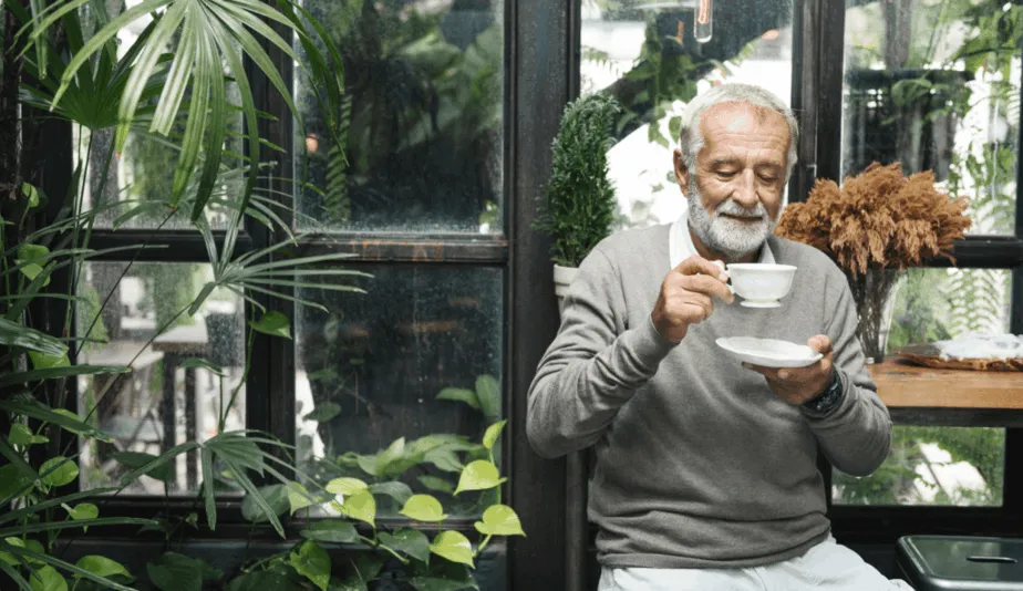 senior man drinking from a cup in a garden
