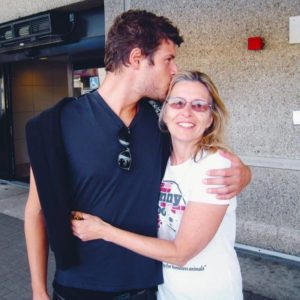 max and kathy 768x768 1 a young man holding and kissing an older woman on the forehead