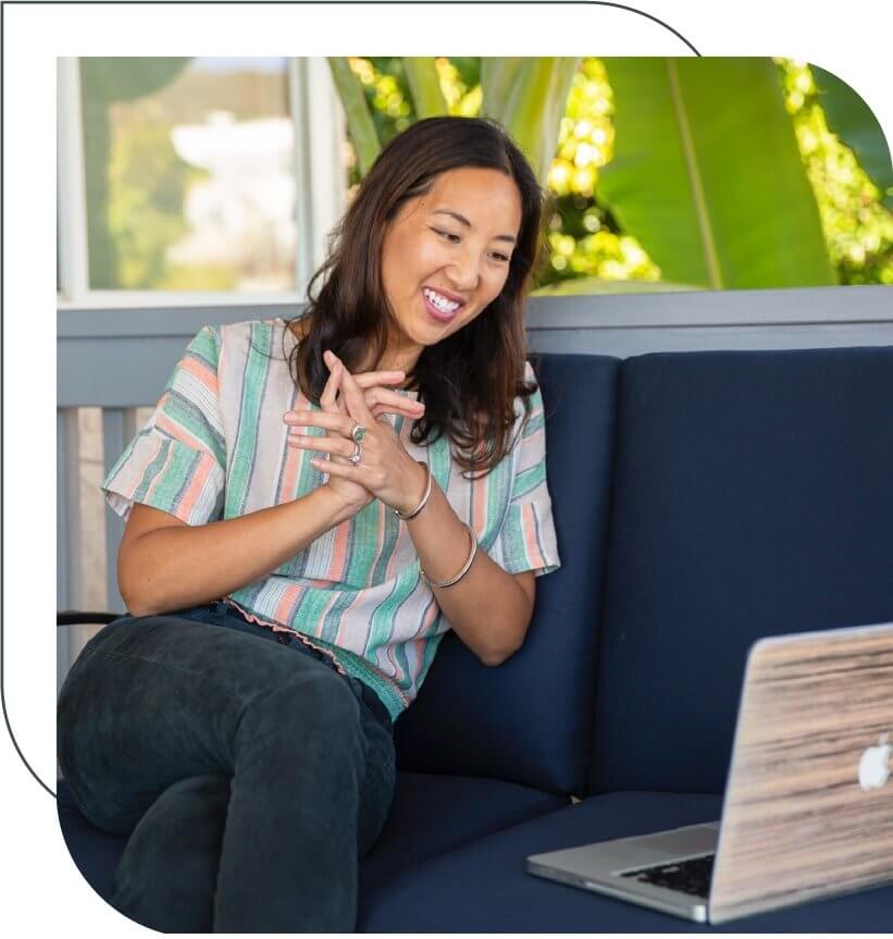 cyn meyer, founder of second wind movement and a certified retirement life coach, sitting on a couch, looking at her laptop and smiling