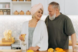 image7 older woman squeezing a lemon in a glass of water and smiling at a senior man standing behind her