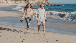 older man and woman walking on the beach