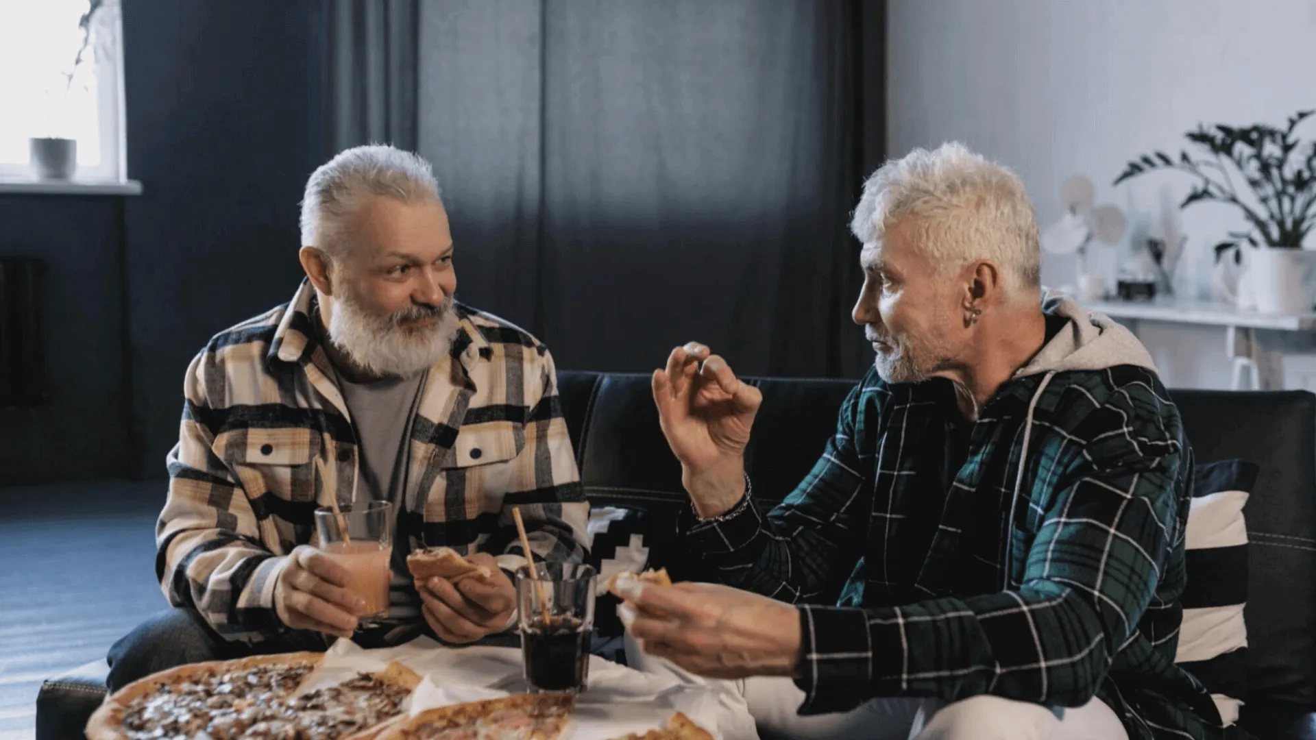 two male senior friends talking and eating pizza