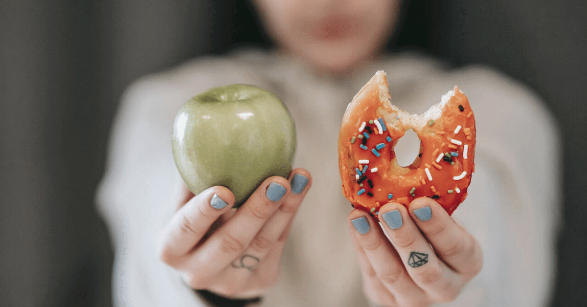 woman holding an apple and a doughnut