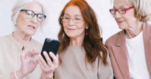 three senior women looking at a phone and smiling