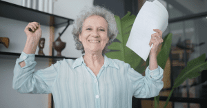 senior woman holding up pieces of paper and laughing