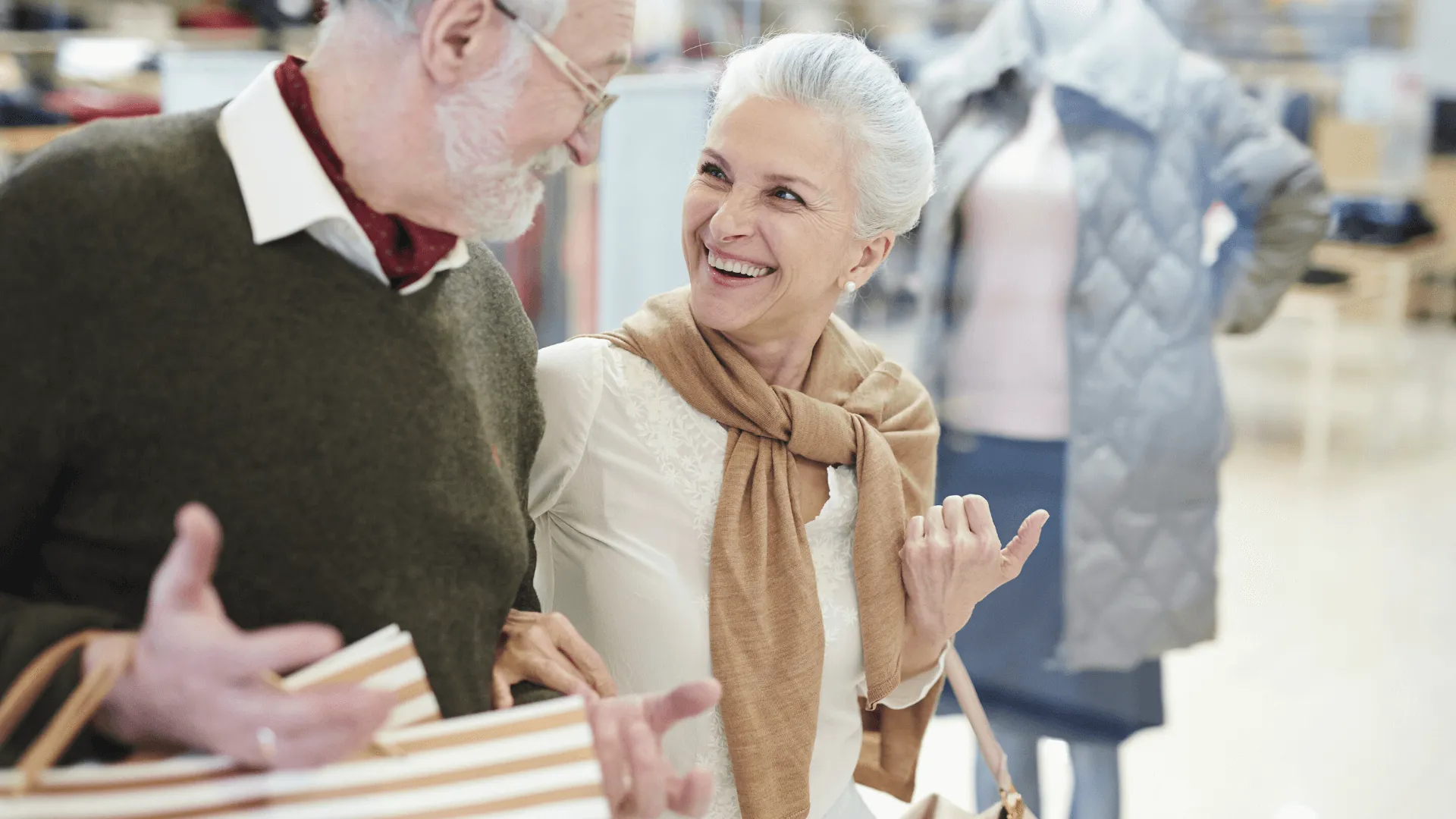 an elderly couple shopping in a mall smiling at each other