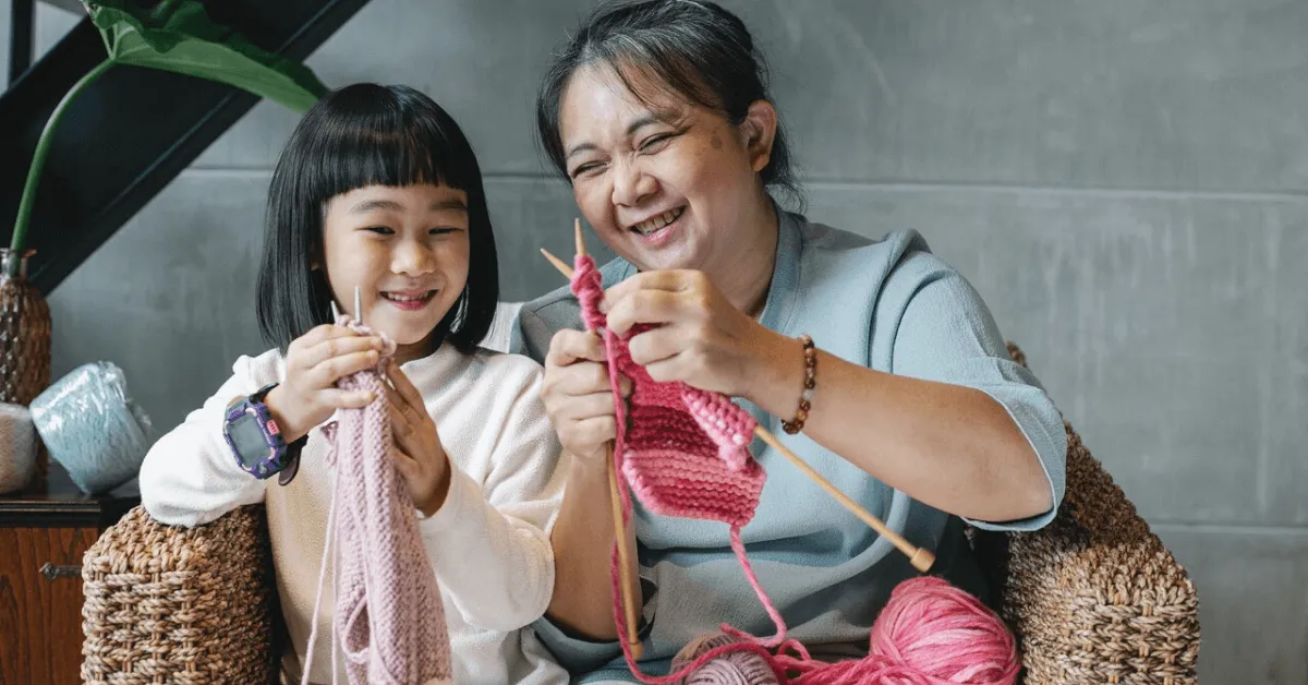 senior woman knitting and laughing with a young girl