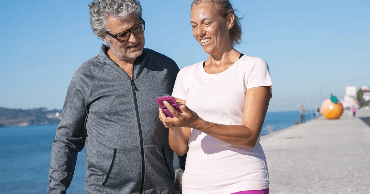 two older adults on the pier looking at a smartphone and laughing