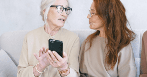 two older women holding a smartphone and talking
