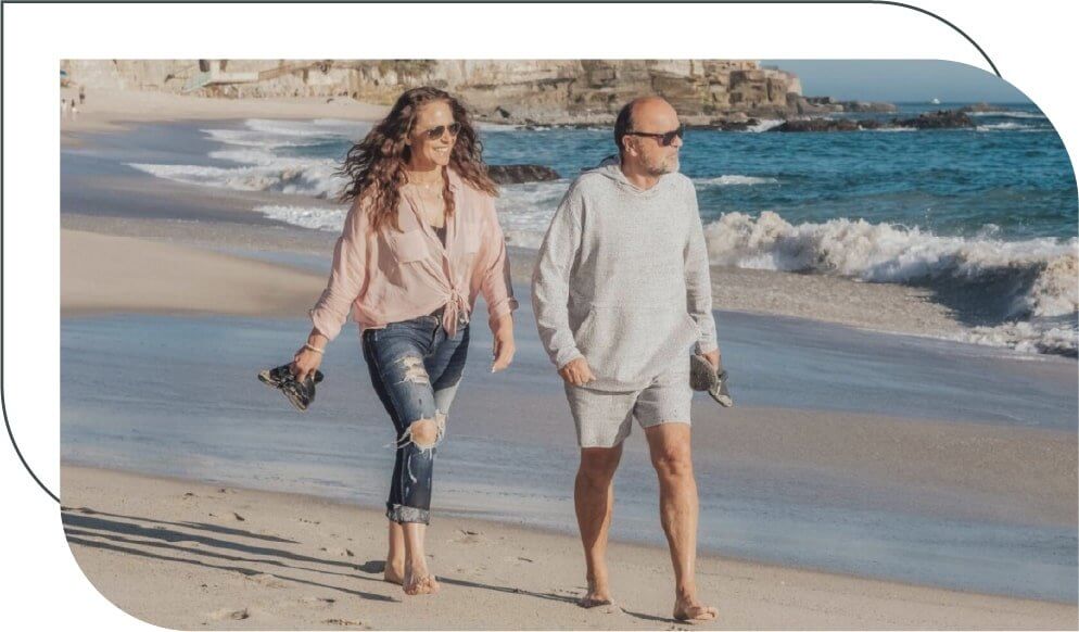 senior couple walking on the beach barefoot