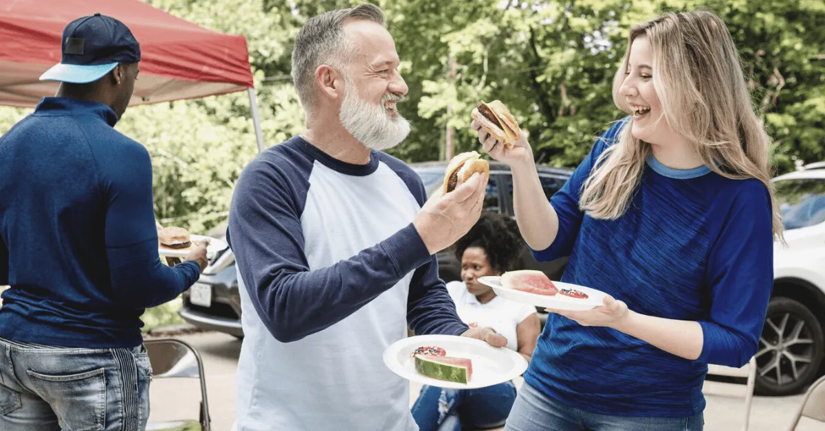 senior man eating and talking to a younger woman at a barbecue