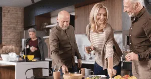 two senior couples eating and drinking in a kitchen