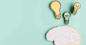 cardboard brain on a light green background with light bulbs above it