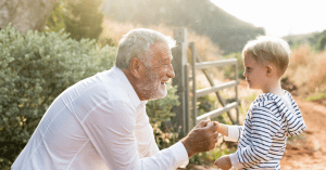 grandpa holding his grandkids hand in a sunny farm