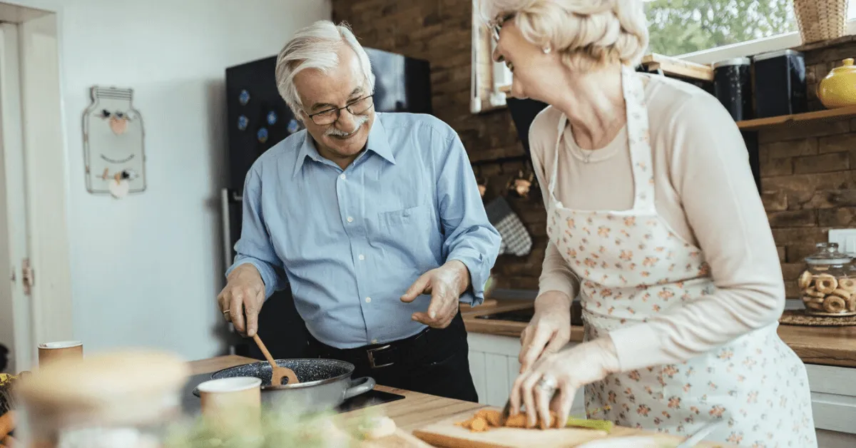 senior couple laughing and cooking in the kitchen