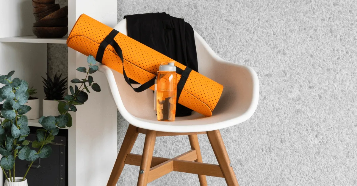 an orange yoga mat and a bottle of water on a chair