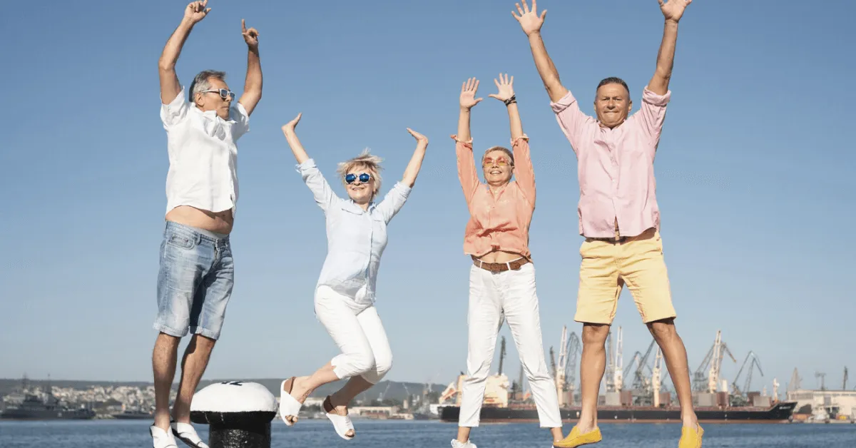 a group of happy seniors jumping on a pier