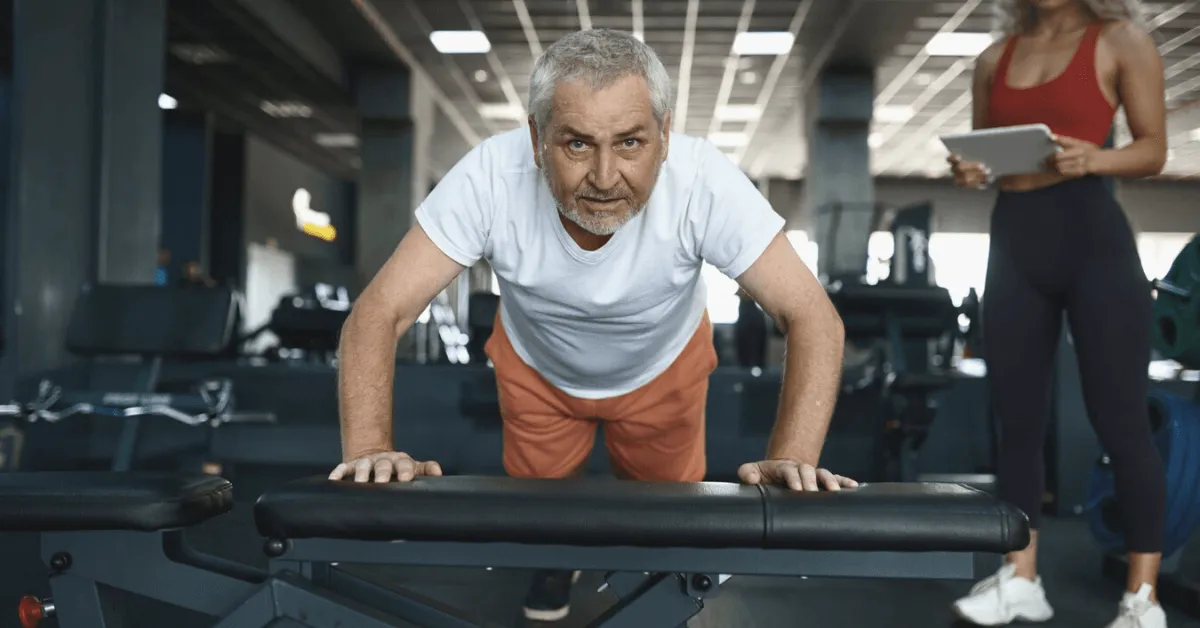 senior man doing push ups at the gym on a bench