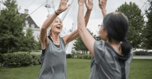 two older women highfiving each other in a park
