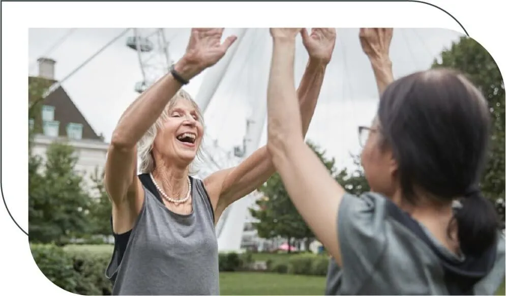 two older women high-fiving in a park