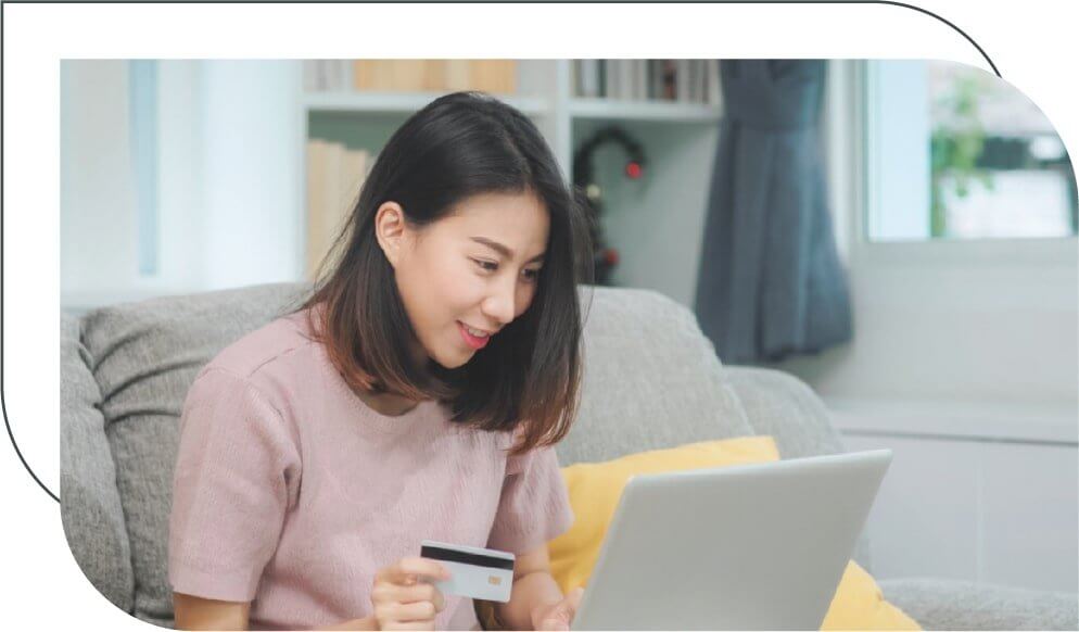 woman sitting on a couch paying through her laptop with a credit card