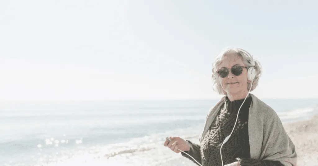 senior woman walking on the beach with headphones