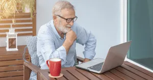 senior man sitting at a desk looking at a laptop
